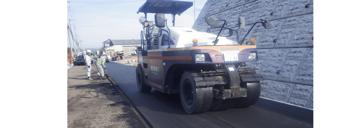 重機を使って道路の塗装工事をする様子